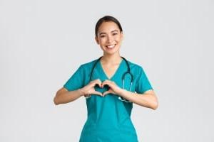 Smiling Asian nurse forming a heart with her hands