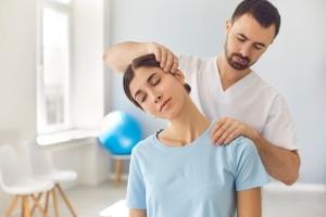 Physical therapy professional manipulating a woman's neck and shoulders