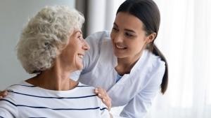 Elderly woman smiling at a young nurse over her shoulder