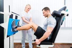 Physical therapy professional helping a male athlete use equipment